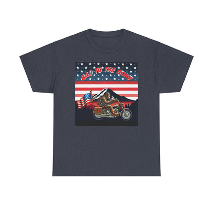 This tee has bigfoot riding on a motorcycle with an American flag hanging off the back. he's riding in front of a mountain that's in front of a patriotic background of stars and stripes. This tee is gray