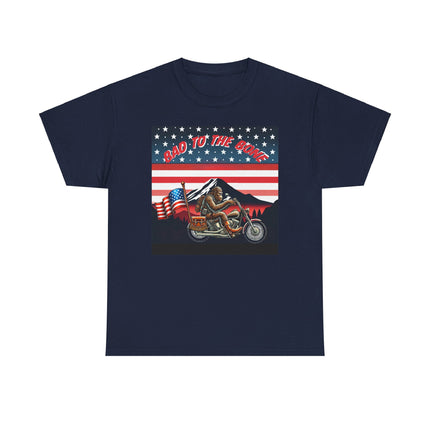 This tee has bigfoot riding on a motorcycle with an American flag hanging off the back. he's riding in front of a mountain that's in front of a patriotic background of stars and stripes. This tee is navy