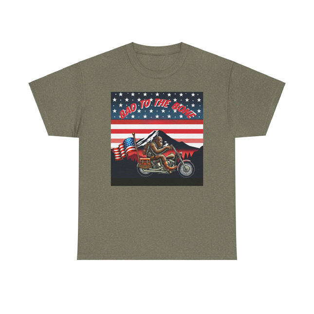 This tee has bigfoot riding on a motorcycle with an American flag hanging off the back. he's riding in front of a mountain that's in front of a patriotic background of stars and stripes. This tee is army green